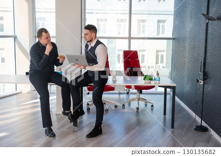 Two Caucasian men discussing work in an office. Businessman with a hearing aid.  130135682