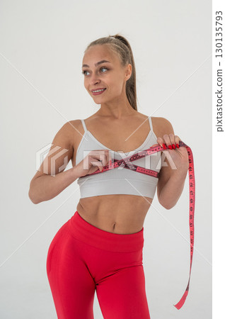 Young woman measuring her chest circumference on white background. 130135793