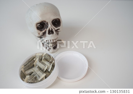 Skull Chewing Tobacco on a White Table. 130135831