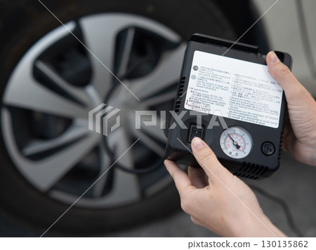 Woman holding a car tire pump.  130135862