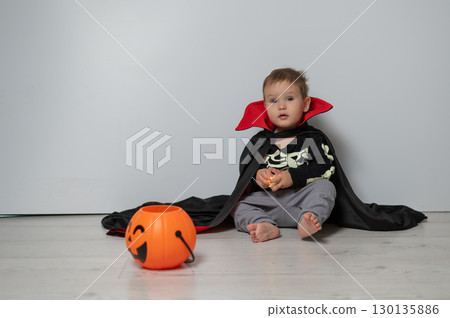 Little Caucasian boy in Dracula costume holding basket for sweets on white background. Trick or treat. Little Caucasian boy in Dracula costume holding basket for sweets on white background. Trick or treat. 130135886