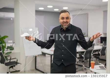 Caucasian man launching paper airplane in office.  130135917
