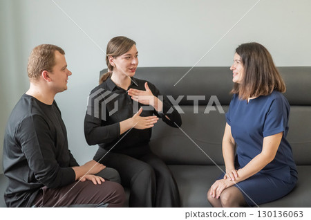 A man and two women are talking in Russian sign language.  130136063