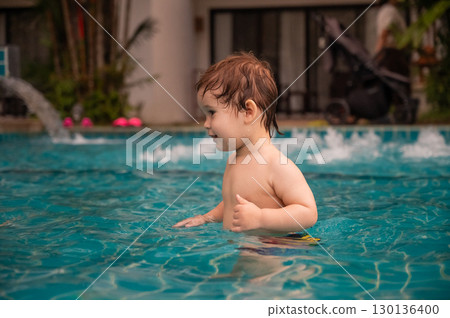 Caucasian one year old boy playing ball in swimming pool.  130136400