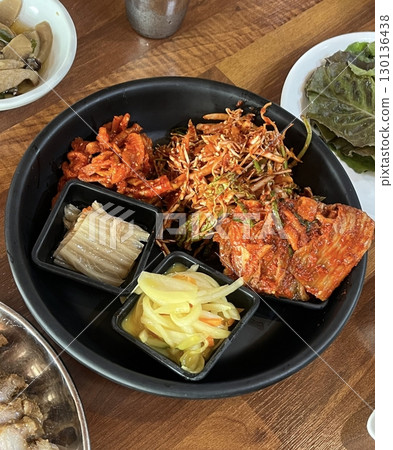 An assortment of colorful banchan, featuring kimchi, seasoned vegetables, pickled radish, and marinated seaweed. These Korean side dishes bring a variety of textures and flavors to the table. 130136438