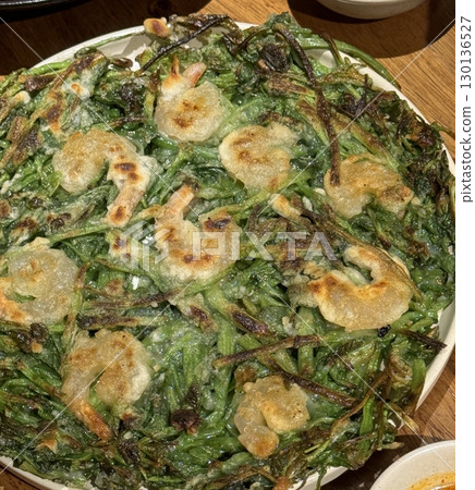 A crispy haemul pajeon, Korean seafood pancake packed with green onions and fresh seafood. Golden brown and savory, its a perfect dish for sharing or enjoying as a snack. A crispy haemul pajeon, Korean seafood pancake packed with green onions and fresh seafood. Golden brown and savory, its a perfect dish for sharing or enjoying as a snack. 130136527