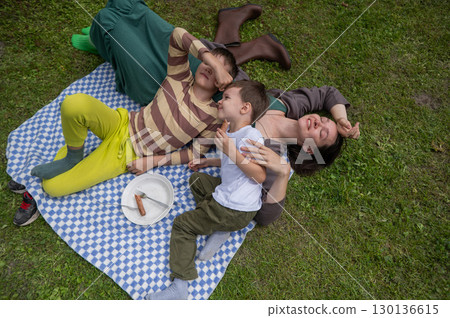 Caucasian woman eats fried sausages with her sons at a picnic. Caucasian woman eats fried sausages with her sons at a picnic. 130136615