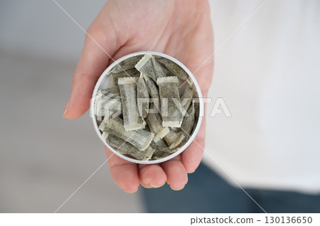A woman holds a jar of chewing tobacco.  130136650
