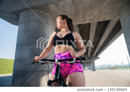 Caucasian woman in short shorts riding a bicycle. Caucasian woman in short shorts riding a bicycle. 130136664