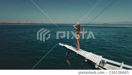 Aerial drone footage of a beautiful tourist enjoying the stunning landscape of Komodo National Park from a traditional Indonesian boat, capturing the essence of tropical adventure and wanderlust 130136665
