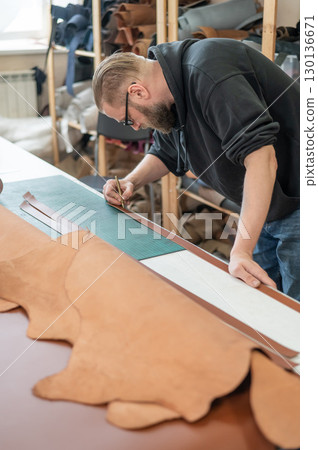 Caucasian bearded man working as a tanner in a workshop. Caucasian bearded man working as a tanner in a workshop. 130136671