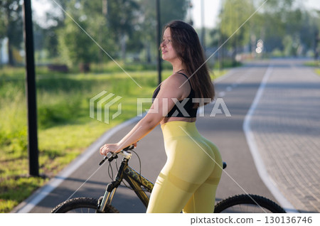 Curvy Caucasian Woman Riding Bicycle in Park.  130136746