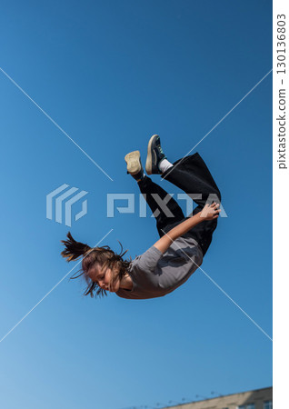 A girl jumps on an outdoor trampoline. 130136803