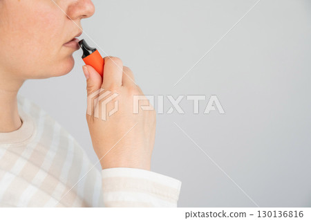 Caucasian woman smoking disposable vape.  130136816