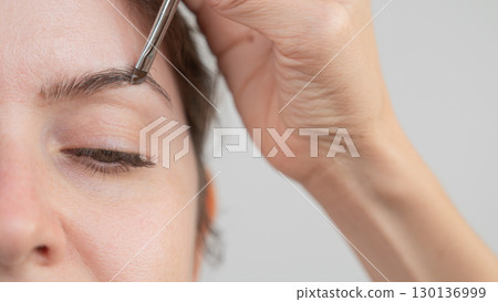 Caucasian woman getting eyebrow tinting procedure. Caucasian woman getting eyebrow tinting procedure. 130136999