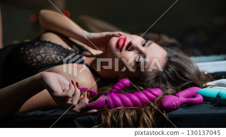 Beautiful brunette in lace lingerie holds pink dildo.  130137045