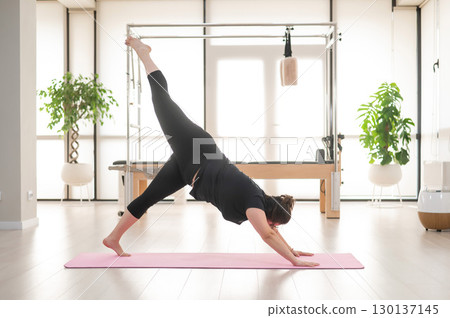 A plump woman does Pilates in a studio.  130137145