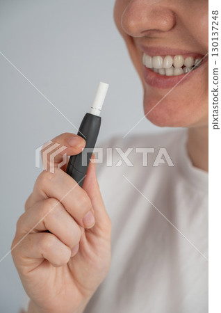 Woman smoking tobacco heating system. Electronic cigarette. Woman smoking tobacco heating system. Electronic cigarette. 130137248