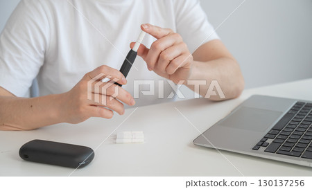 A woman inserts a cigarette stick into a tobacco heating system. Electronic cigarette. 130137256