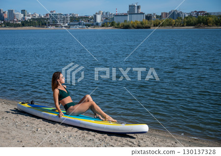 Caucasian woman posing on a SUP board. Summer sport. Caucasian woman posing on a SUP board. Summer sport. 130137328