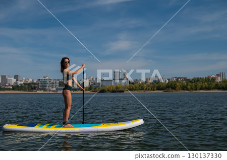 Caucasian woman riding a SUP board on the lake. Summer sport. Caucasian woman riding a SUP board on the lake. Summer sport. 130137330