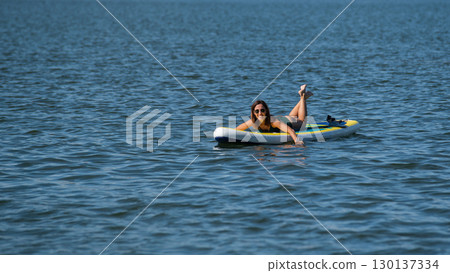 Caucasian woman posing on a SUP board. Summer sport. 130137334