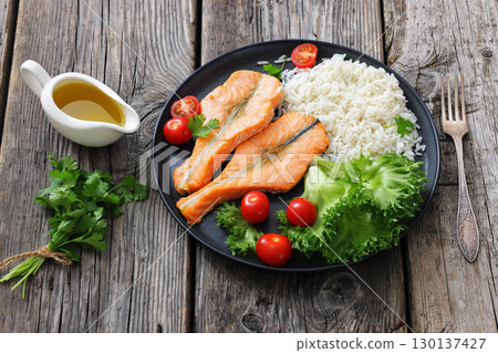 baked salmon steaks with rice, lettuce, tomatoes 130137427