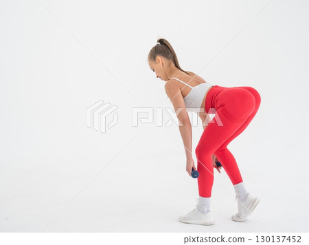 Young woman doing exercise with dumbbells on white background. 130137452