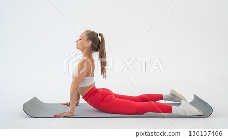 Young woman doing cobra exercises on white background. Young woman doing cobra exercises on white background. 130137466
