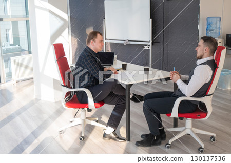 Two Caucasian men negotiating in an office.  130137536