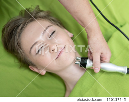 Top view of Caucasian woman undergoing radio wave RF lifting procedure in beauty salon. Top view of Caucasian woman undergoing radio wave RF lifting procedure in beauty salon. 130137545