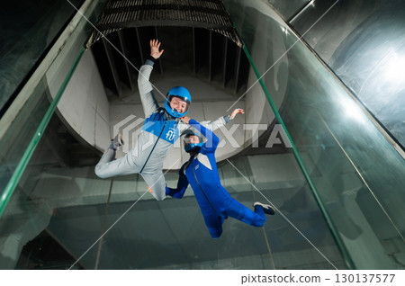 A male instructor teaches a woman how to fly in a wind tunnel. Free fall simulator. 130137577