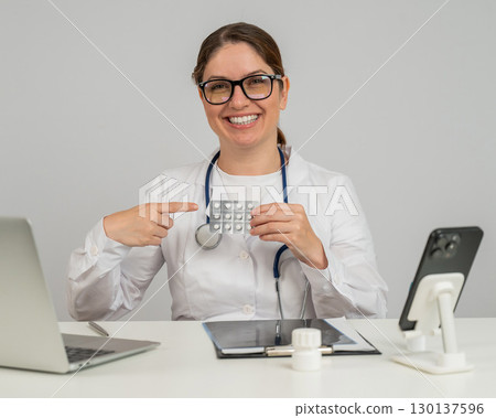 A female doctor sits at a table and recommends pills. A female doctor sits at a table and recommends pills. 130137596