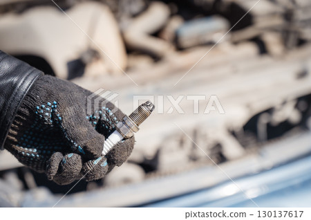 Caucasian man changing spark plugs in car. Caucasian man changing spark plugs in car. 130137617