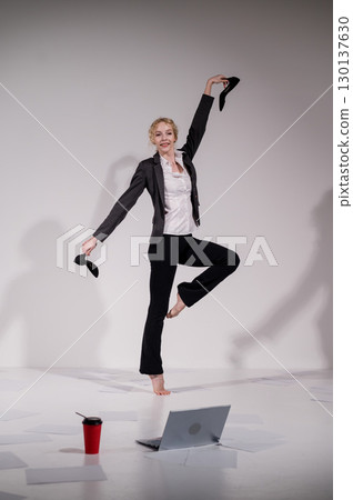Barefoot ballerina dancing in business suit on white background. Barefoot ballerina dancing in business suit on white background. 130137630