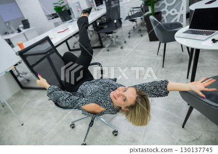 Caucasian woman having fun and lying on office chair. Caucasian woman having fun and lying on office chair. 130137745