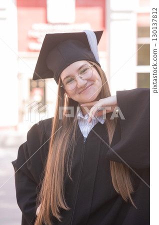 Young happy caucasian woman in graduation gown.  130137812