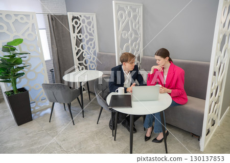 Colleagues are sitting at a laptop and discussing work.  130137853