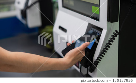 A woman pays using her smartphone at a self-checkout. A woman pays using her smartphone at a self-checkout. 130137936
