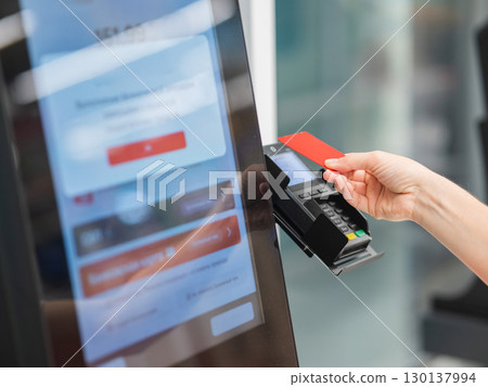 Woman paying with credit card at self-checkout.  130137994