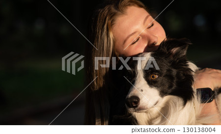 Young Caucasian woman hugging her border collie dog while walking in the park.  130138004