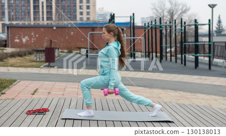 Young woman doing fitness exercises with dumbbells outdoors. Young woman doing fitness exercises with dumbbells outdoors. 130138013
