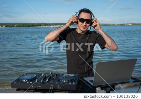 Male DJ playing music on the beach.  Male DJ playing music on the beach.  130138020