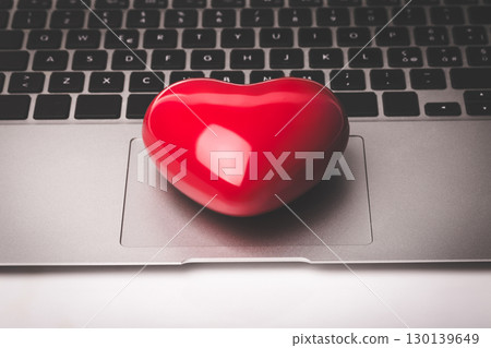 Vibrant Red Heart Symbol Resting on Modern Laptop Trackpad Representing Digital Love and Online Romance Connection Vibrant Red Heart Symbol Resting on Modern Laptop Trackpad Representing Digital Love and Online Romance Connection 130139649