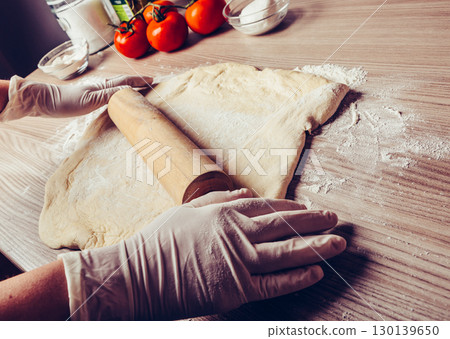 Chef Rolling Fresh Pasta Dough with Wooden Pin in Sunlit Italian Kitchen 130139650
