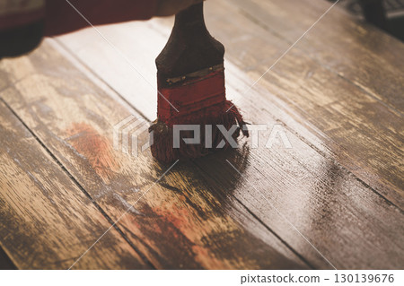 Worn Paintbrush Creating Rich Brown Strokes on Weathered Wooden Surface During Artistic Process 130139676