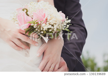 Newlywed Couple Embracing with Delicate Pink Rose and Baby's Breath Bridal Bouquet on Wedding Day 130139689