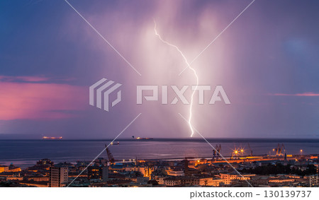 Massive cloud to ground lightning bolts hitting the horizon of city lights 130139737