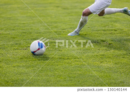 Athletes with a ball play football on the grass 130140144