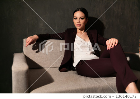 woman in business suit sitting on gray office sofa 130140172